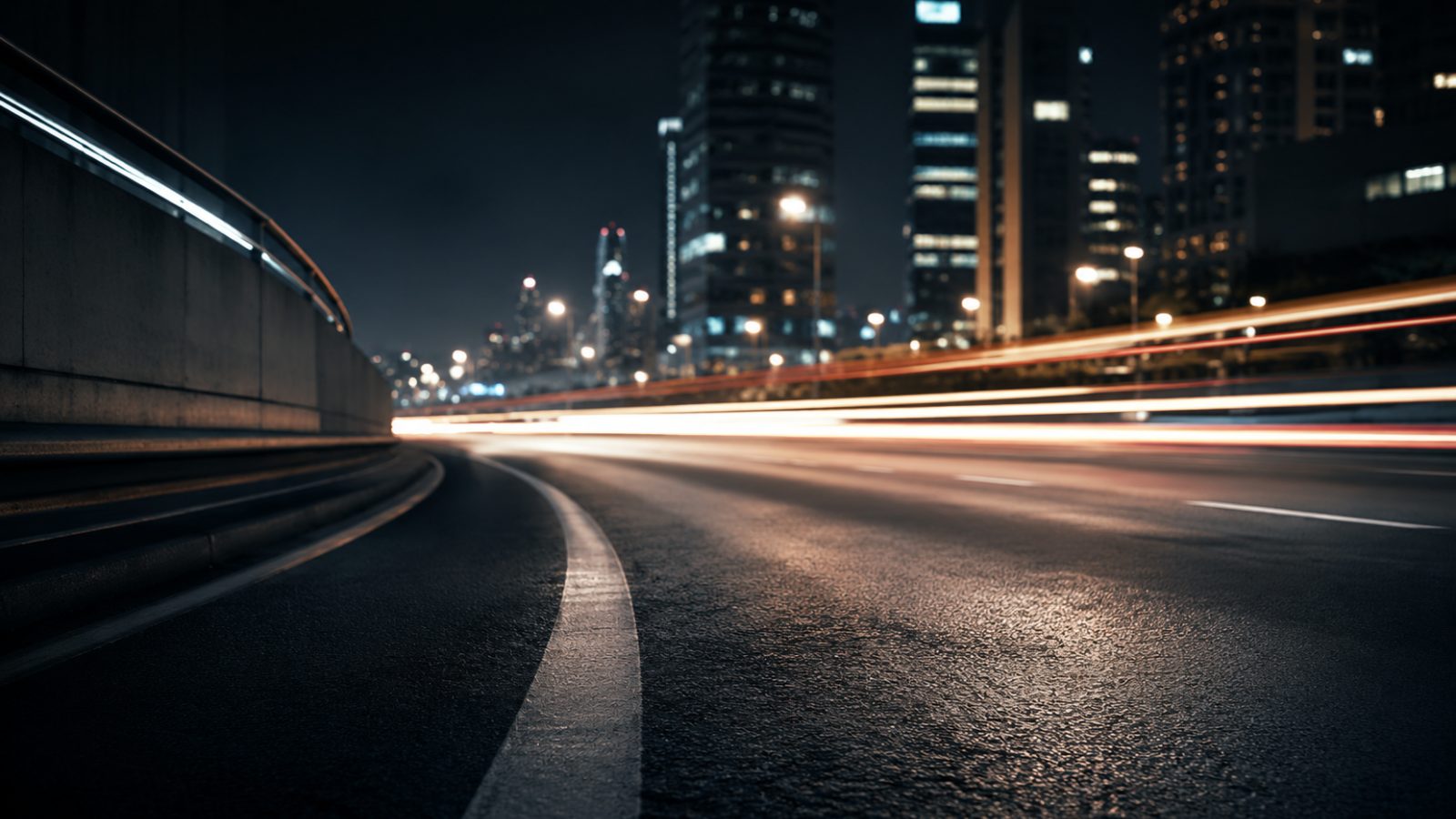 Dark urban road at night with light trails, representing market entry, mobility, and launch momentum.